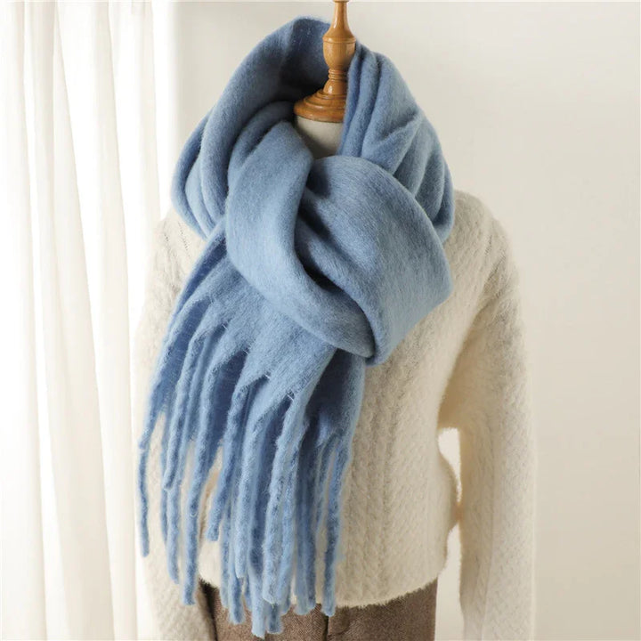 Cozy light blue wool scarf with fringes styled on mannequin wearing cream knit sweater