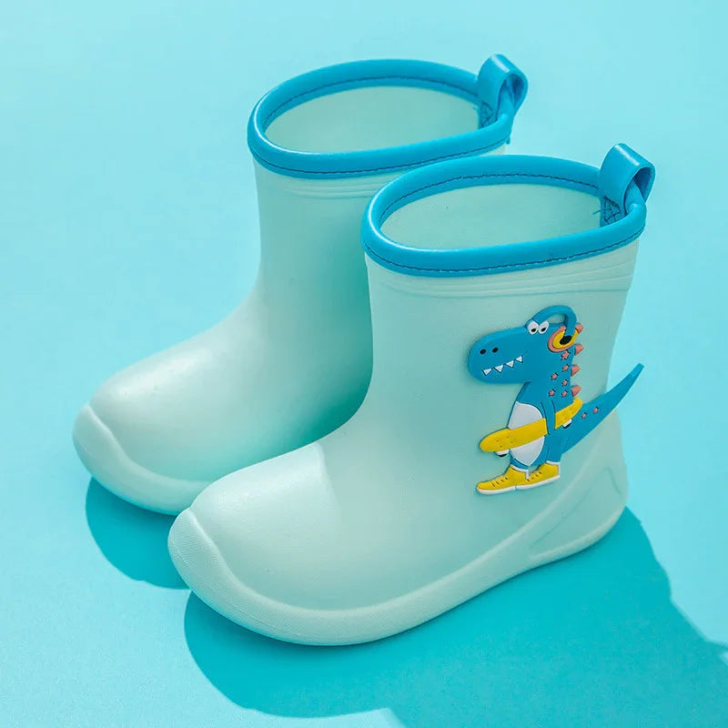 Light blue children's rain boots with dinosaur graphic and blue trim on a blue background