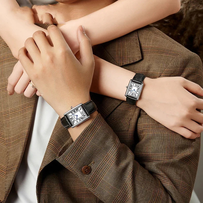 Couple wearing matching square silver watches with black leather straps and Roman numeral dials