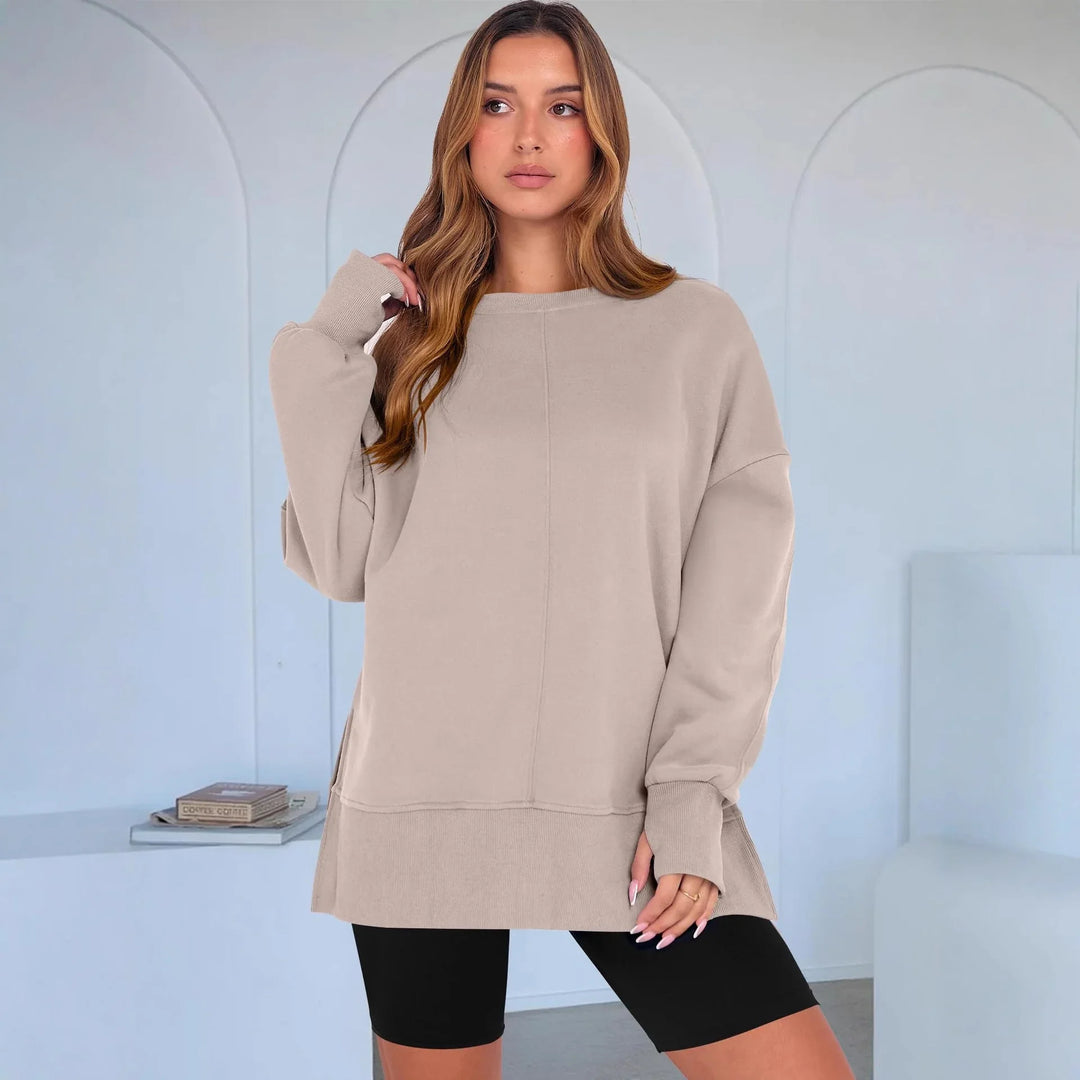 Woman wearing beige oversized sweatshirt and black cycling shorts in minimalist modern room