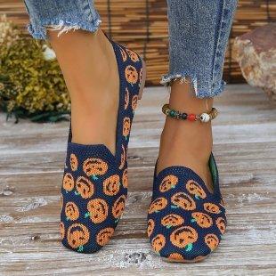 Pair of blue slip-on shoes with orange pumpkin patterns worn with frayed hem jeans and a beaded ankle bracelet