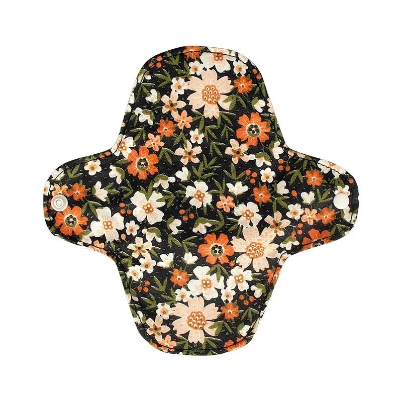 Reusable cloth menstrual pad with black background and orange and white floral pattern