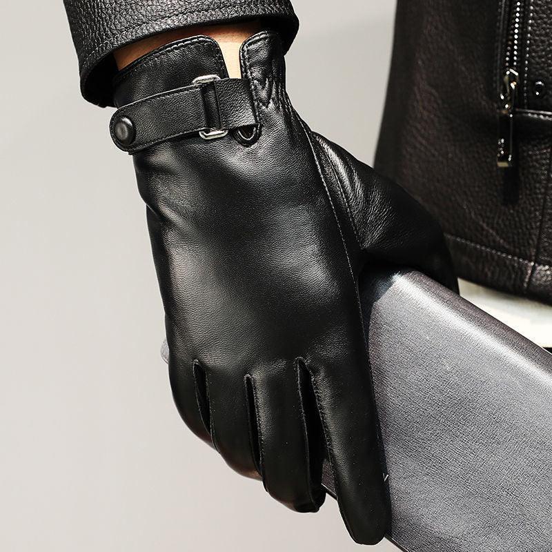 Close-up of black leather glove with button strap holding a gray textured wallet