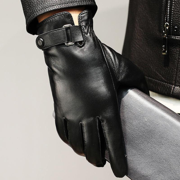 Close-up of black leather glove with button strap holding a gray textured wallet