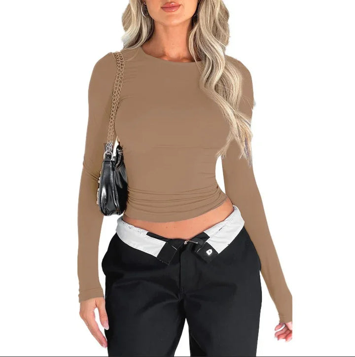 Woman wearing fitted beige long sleeve top with black pants and black shoulder bag