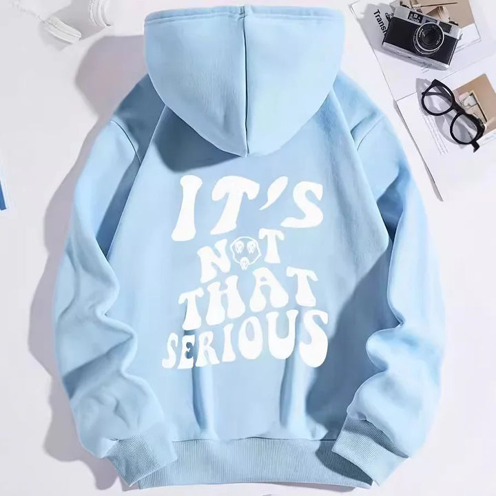 Light blue hoodie with white text saying IT'S NOT THAT SERIOUS on back, styled with vintage camera and glasses