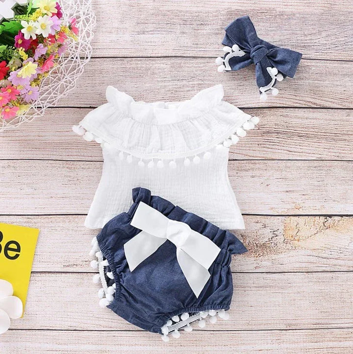 Baby girl summer outfit with white ruffled top, navy shorts with white bow, and matching navy bow headband