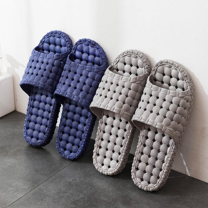 Blue and gray textured open-toe indoor slippers leaning against white wall on gray floor