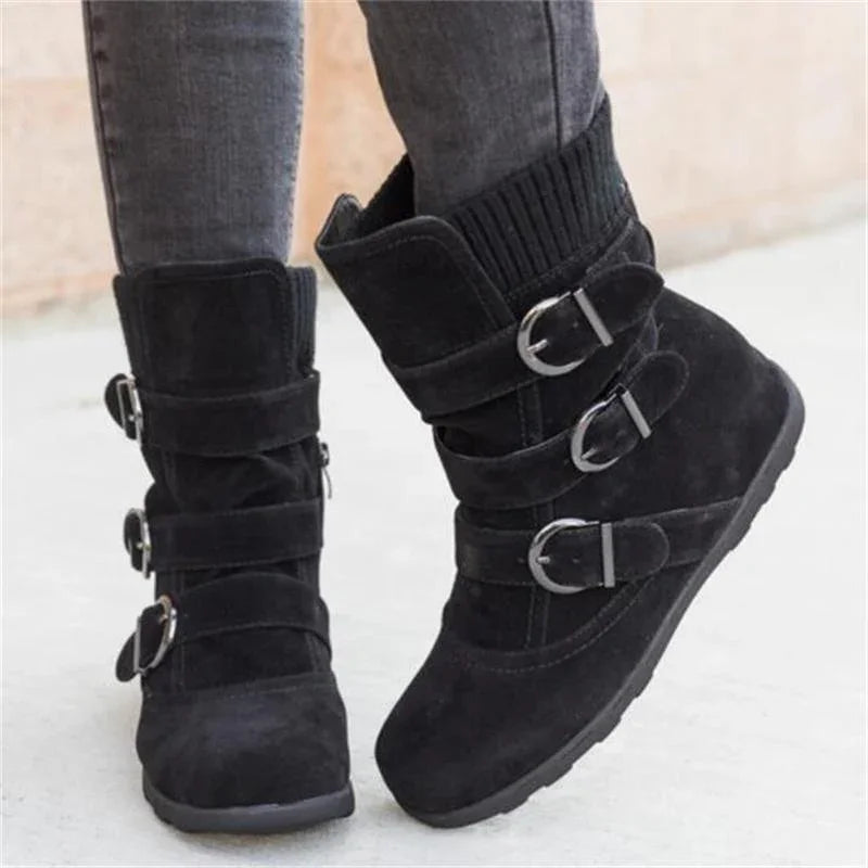 Black suede wedge ankle boots with three buckle straps and ribbed knit collar worn with gray jeans