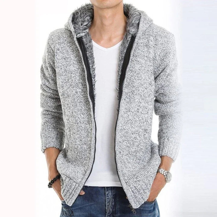 Man wearing grey knitted hooded zip-up fleece jacket over white t-shirt and blue jeans