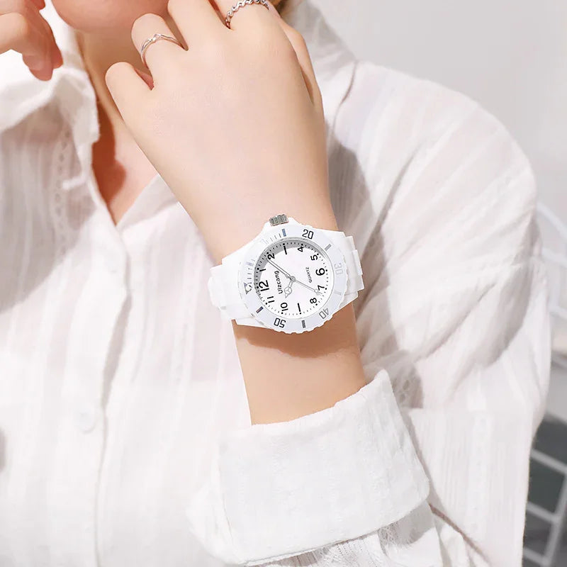 White Uzcanti quartz wristwatch on a woman's wrist wearing a white textured shirt