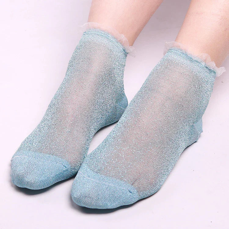 Pair of translucent light blue glitter ankle socks on feet with frilled edges