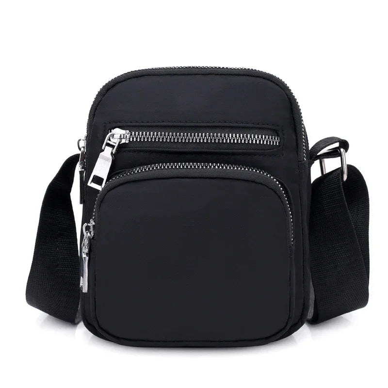 Small black crossbody bag with two zippered compartments and adjustable shoulder strap