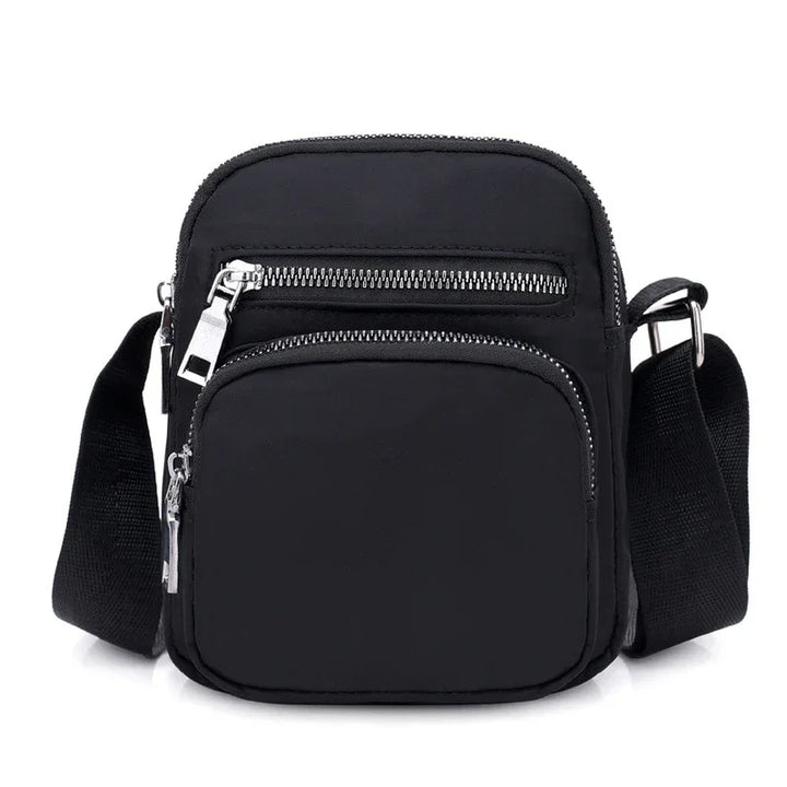 Small black crossbody bag with two zippered compartments and adjustable shoulder strap