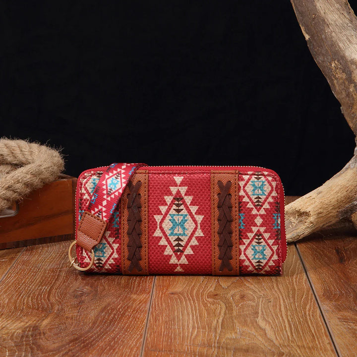Red southwestern-patterned fabric wallet with brown braided leather and matching strap on wood surface