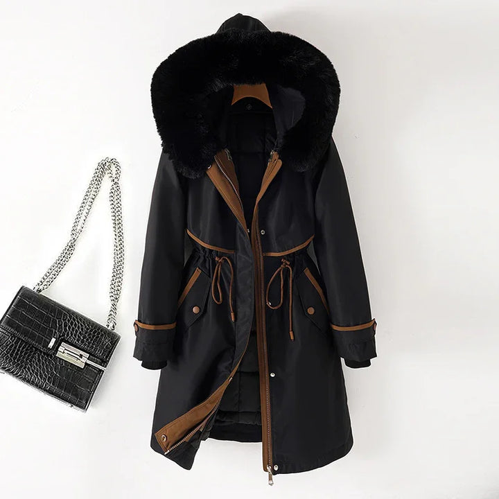 Black winter parka with brown trim and fur-lined hood next to black crocodile leather handbag