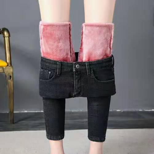 Black slim-fit jeans with soft pink fleece lining showing inside, worn on model legs indoors