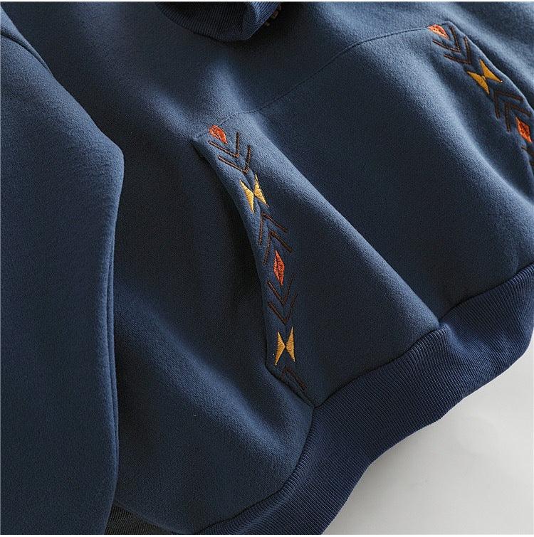 Navy blue hoodie fabric with colorful geometric embroidery detail in orange, yellow, and brown