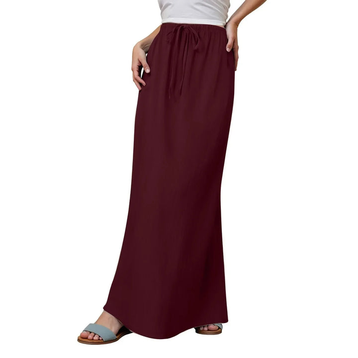 woman wearing burgundy drawstring maxi skirt with white top and blue sandals on white background