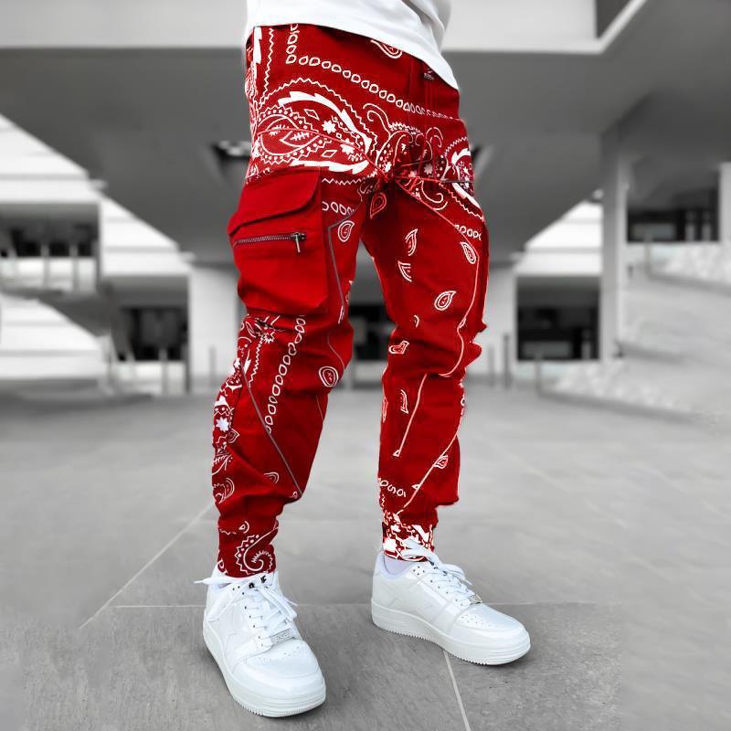 Person wearing red bandana print cargo pants and white sneakers in an outdoor urban setting