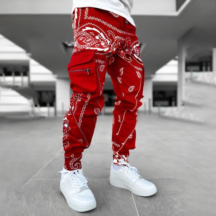 Person wearing red bandana print cargo pants and white sneakers in an outdoor urban setting