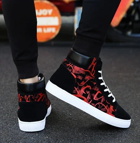 Black and red high-top sneakers with white soles and laces, worn with black pants on asphalt