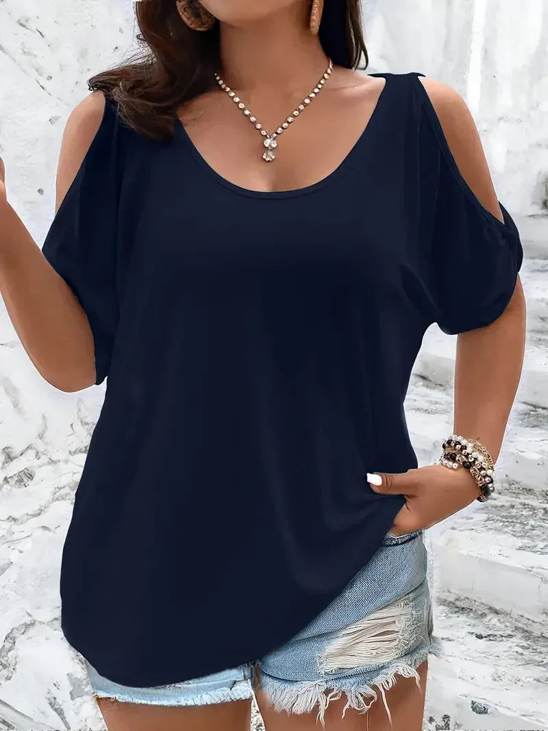 Woman wearing navy cold shoulder top paired with ripped denim shorts and pearl necklace