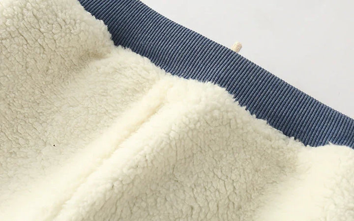 Close-up of cream-colored sherpa fleece fabric with a blue ribbed knit waistband