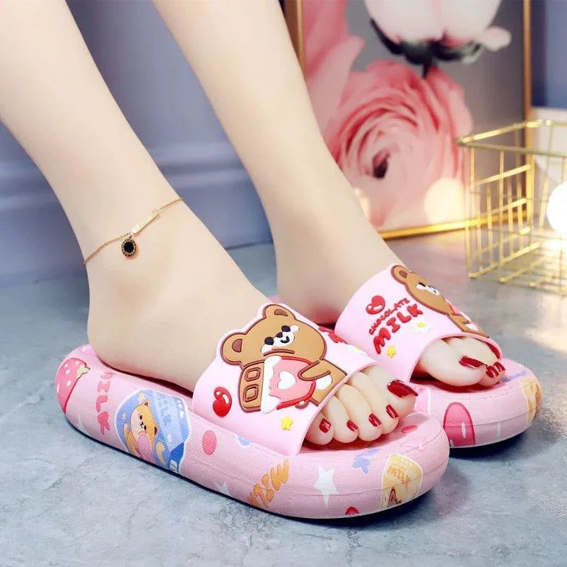 Pink indoor slippers with cute teddy bear design and red nail polish on feet with gold ankle bracelet