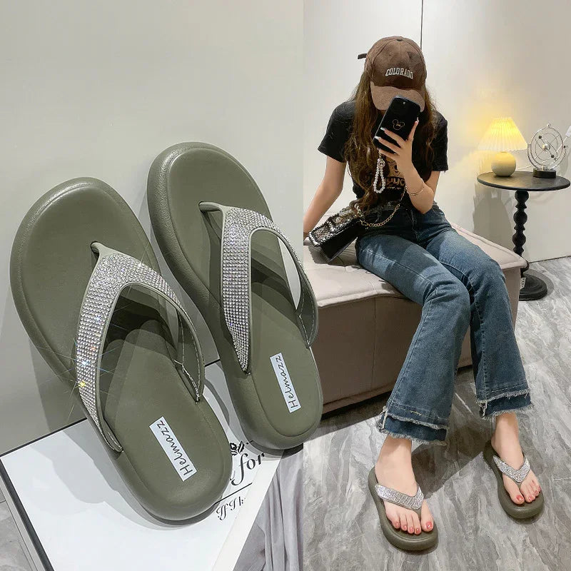 Olive green women's flip flop sandals with rhinestone straps modeled by woman sitting indoors