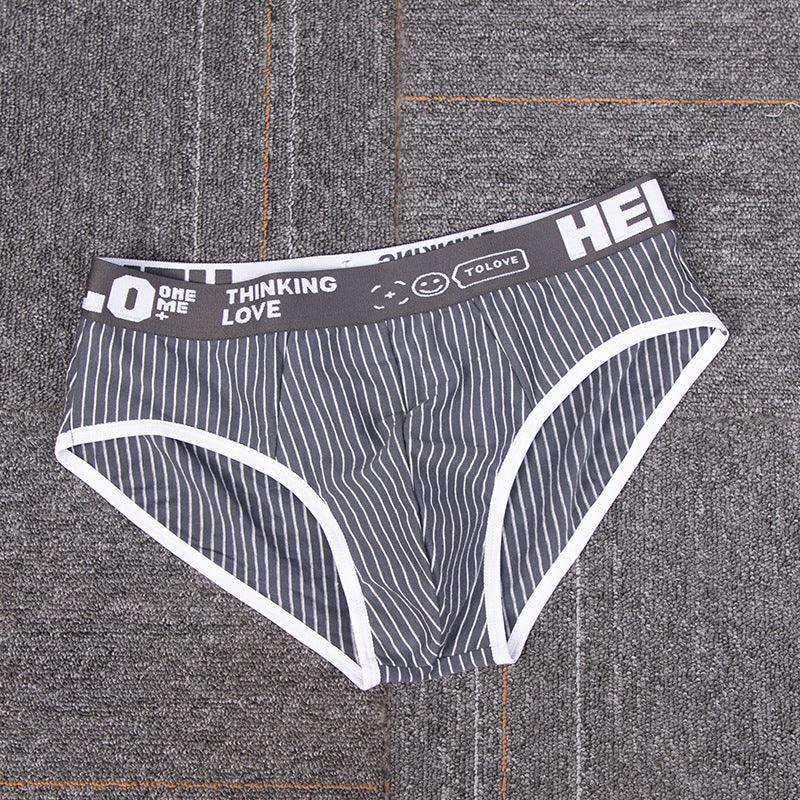 Grey men's briefs with white vertical stripes and printed waistband on textured surface