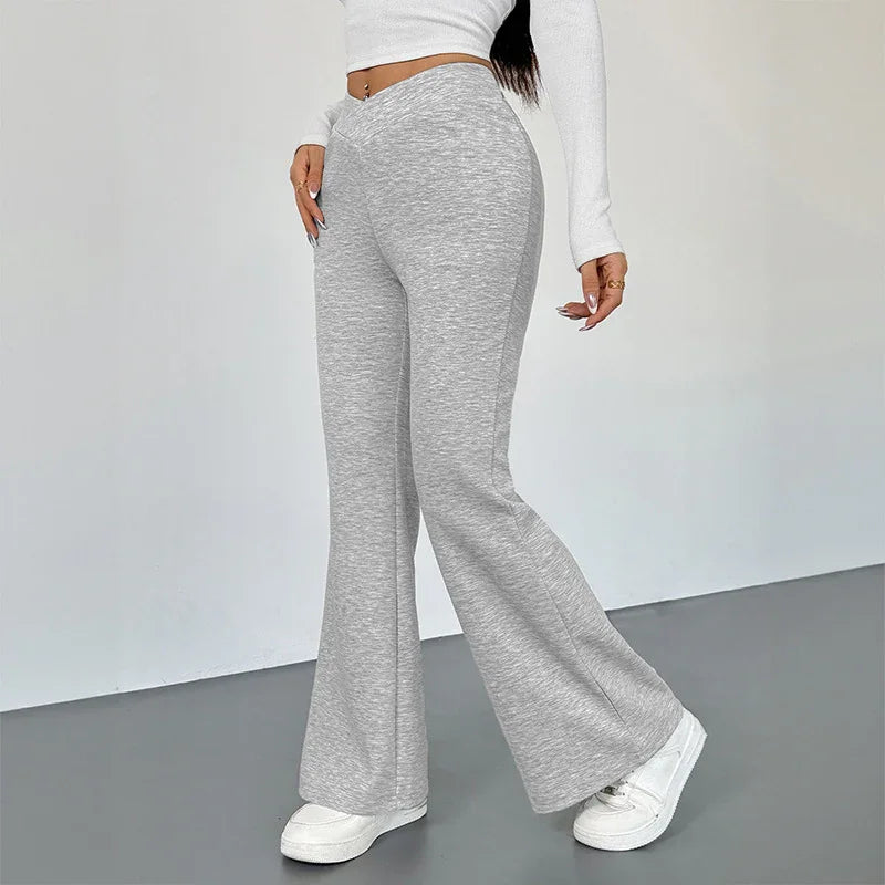 Woman wearing high-waisted light gray flare pants with white sneakers and white cropped long-sleeve top