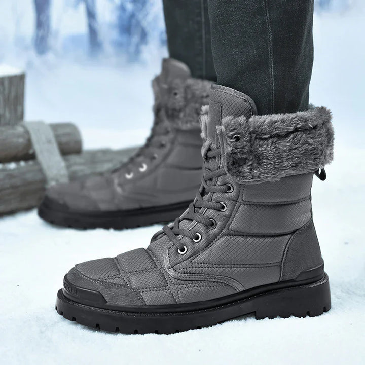 Gray winter boots with faux fur lining worn on snow with logs in background
