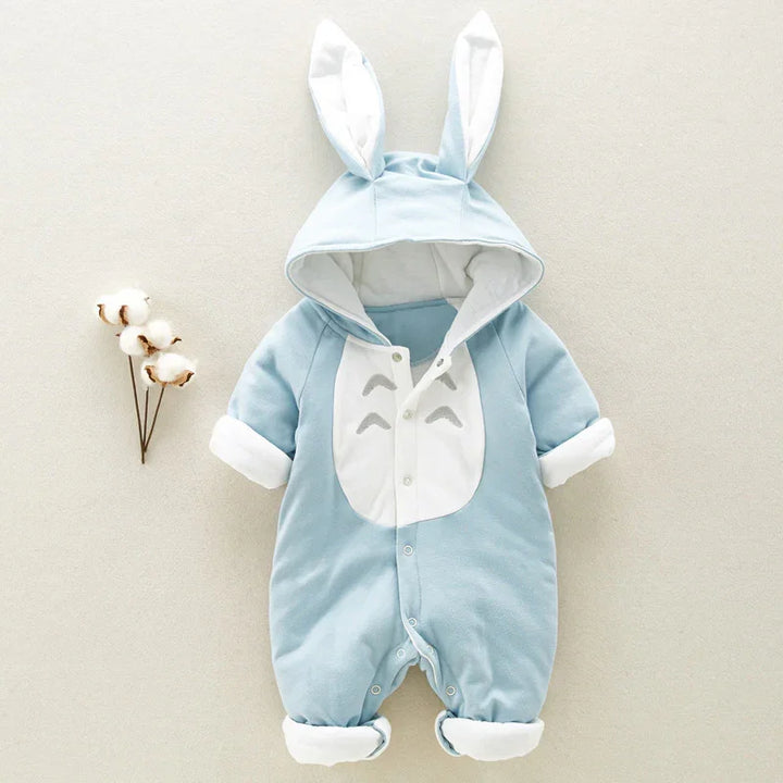 Blue infant onesie with bunny ears hood and white belly detail, laid flat on beige background