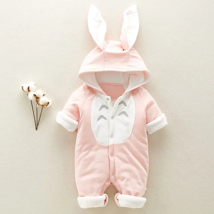 Soft pink baby romper with hood and bunny ears, white front panel, and rolled cuffs on neutral background