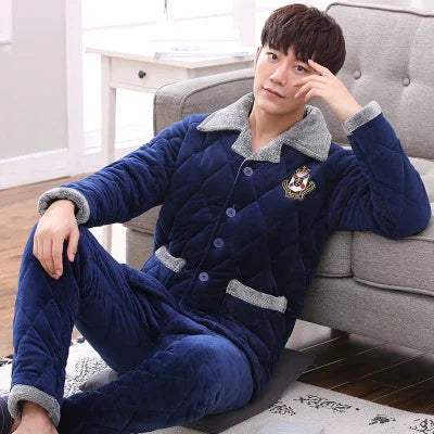 young man relaxing in plush navy blue quilted winter loungewear with gray trim in cozy living room