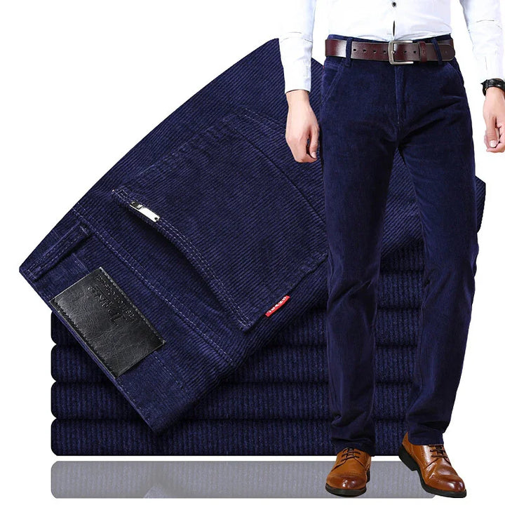 Men's navy blue corduroy pants with brown leather belt and brown shoes, stacked folded pants in background