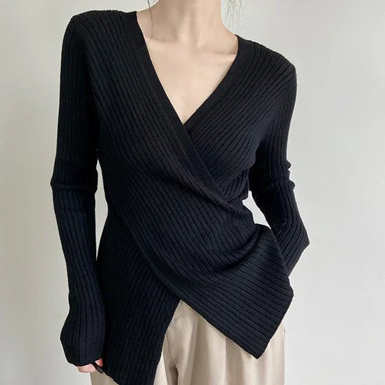 Woman wearing black ribbed knit wrap sweater with V-neck and beige pants