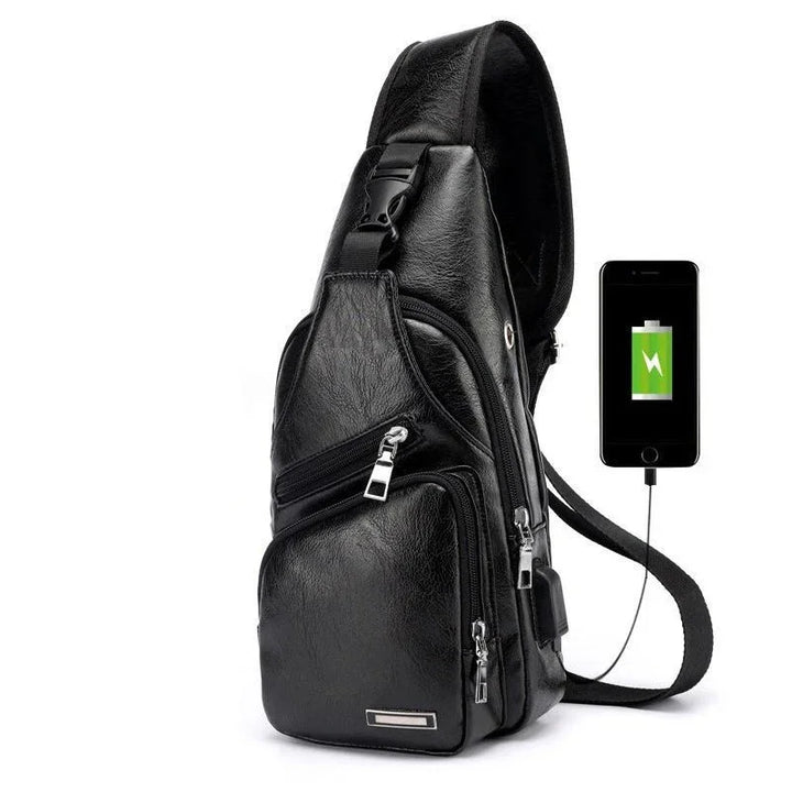 Black leather sling bag with multiple zippered compartments and USB charging port connected to smartphone
