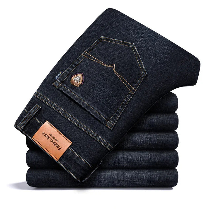 Stacked dark blue denim jeans with stitched back pocket and leather label saying Fashion Jeans
