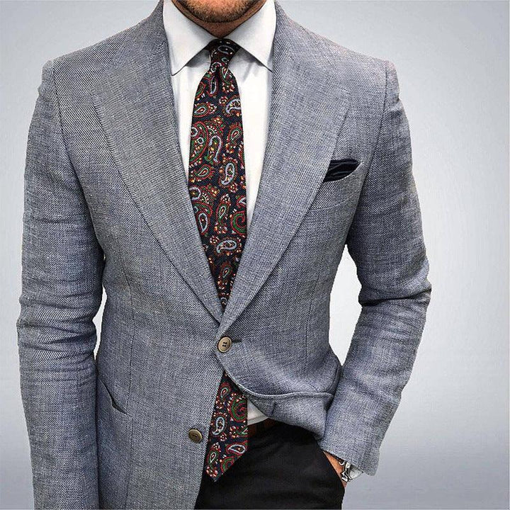 man wearing light gray herringbone blazer with white shirt and colorful paisley tie