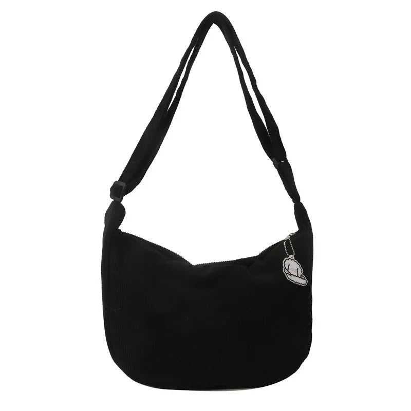 Black shoulder bag with adjustable strap and small white cloud-shaped charm on zipper
