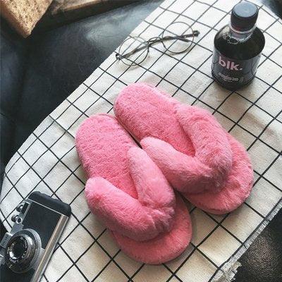 Soft pink fluffy slippers on white grid cloth with a vintage camera, eyeglasses, and a blk water bottle
