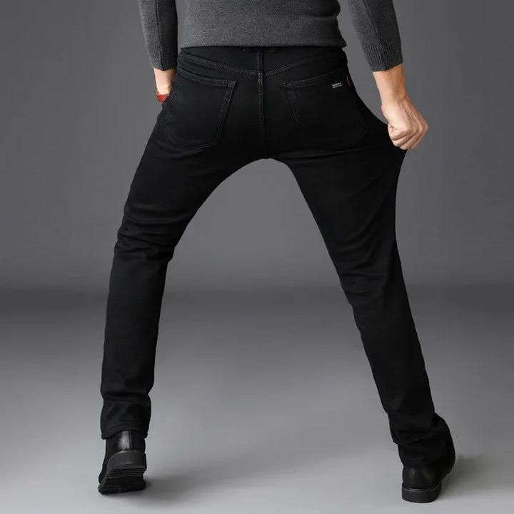 Person stretching slim black jeans back pockets visible on gray background