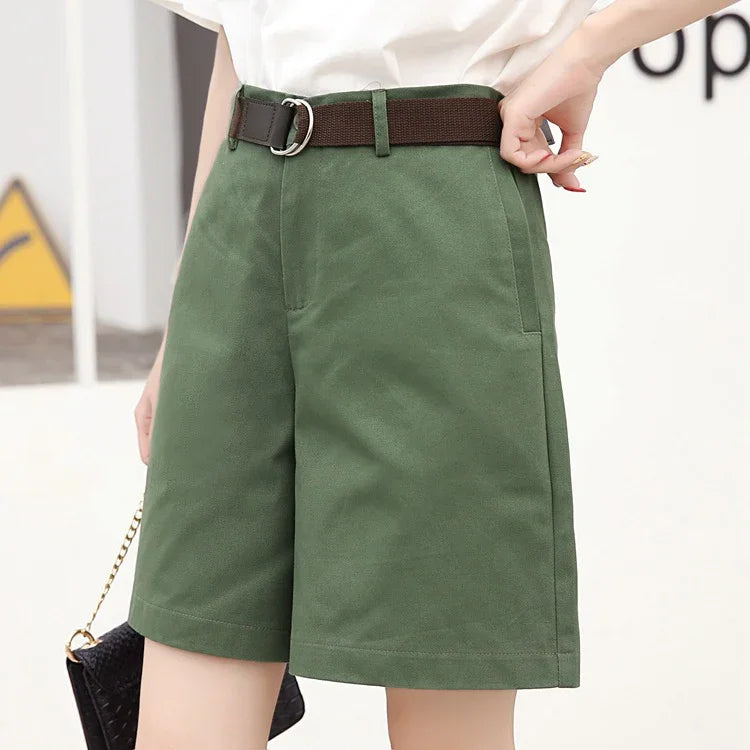 Close-up of woman wearing green high-waisted casual shorts with brown belt and white top