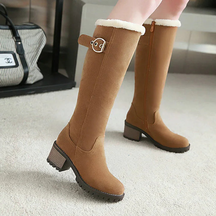 Women wearing knee-high tan suede boots with faux fur lining and buckle detail on carpet