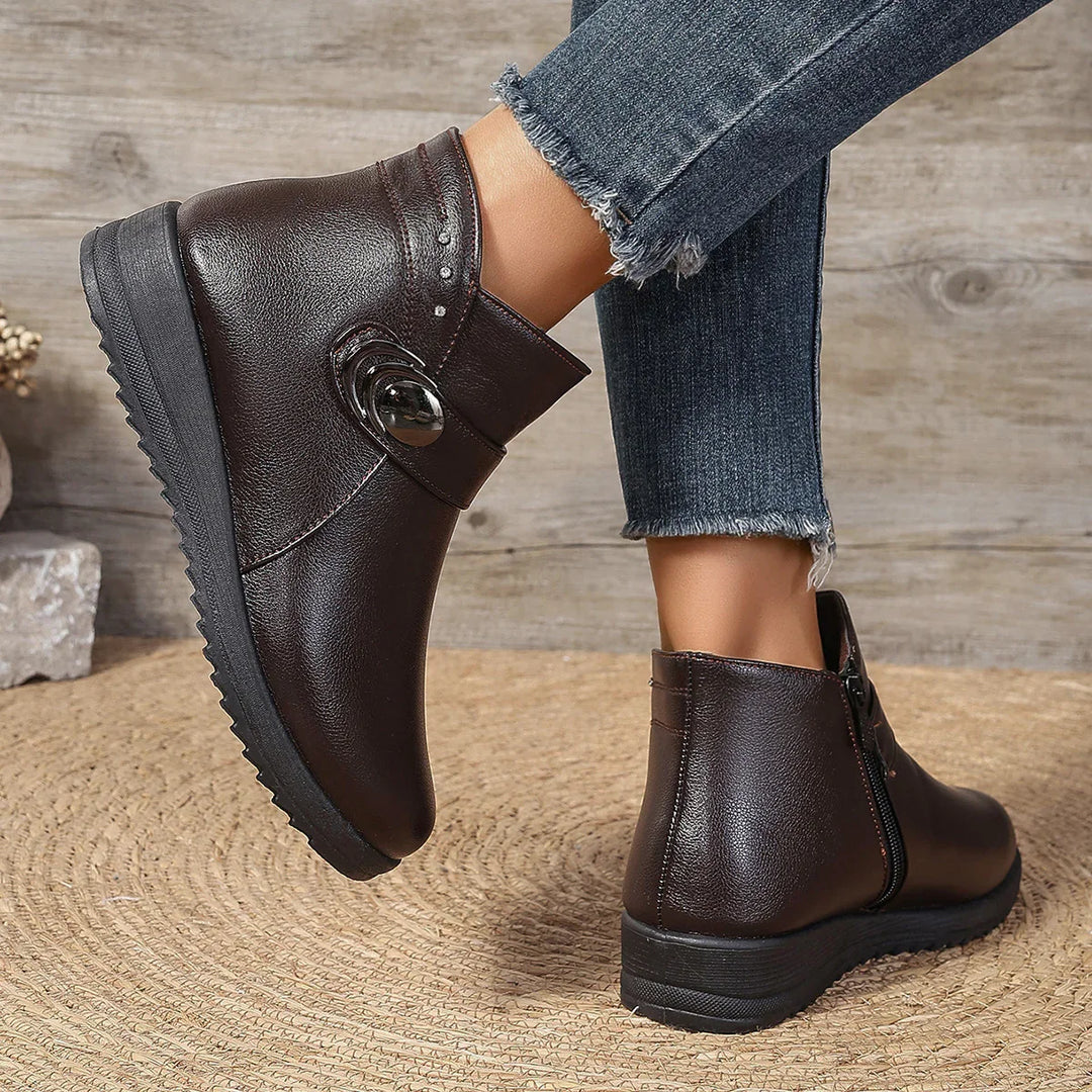 Women wearing dark brown ankle leather boots with zipper and button detail, paired with frayed hem jeans