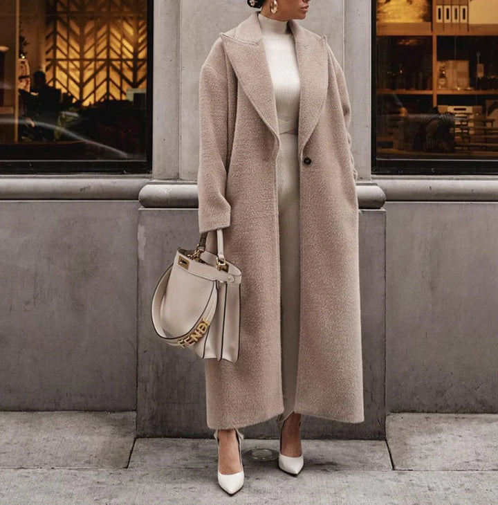 Woman wearing long beige teddy coat, white knit dress, white heels, and holding beige Fendi handbag on city sidewalk