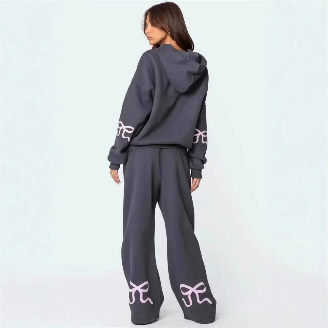 Woman wearing dark gray loose hoodie and wide-leg pants with pink bow designs on sleeves and pant legs