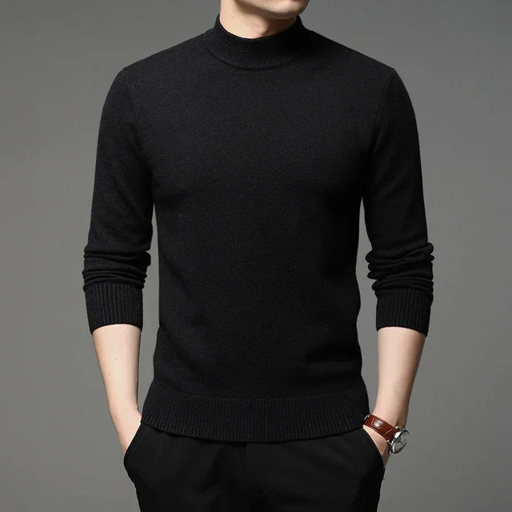 Man wearing a fitted black mock neck sweater with ribbed cuffs and hem, hands in pockets